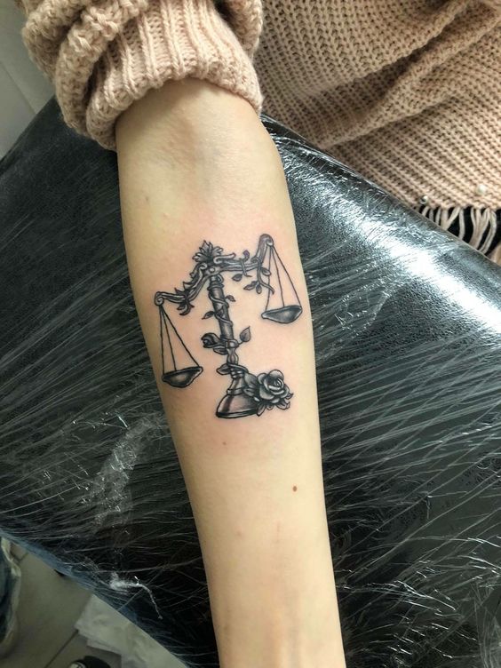 Tatouage Balance Et Rose En Noir Et Gris Sur L'avant Bras