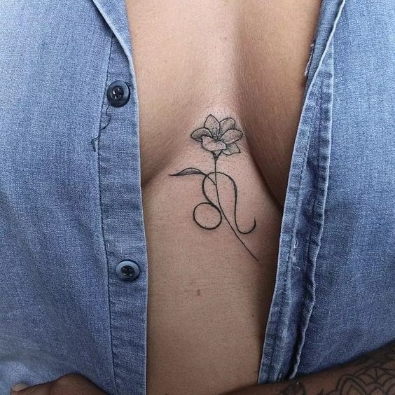 Tatouage Signe Lion Et Fleur En Noir Et Gris Sur Le Sternum