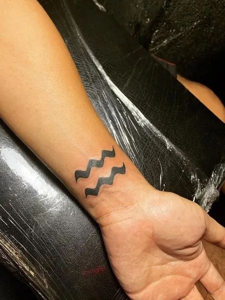 Tatouage Signe Verseau à L'encre Noire Sur Le Poignet