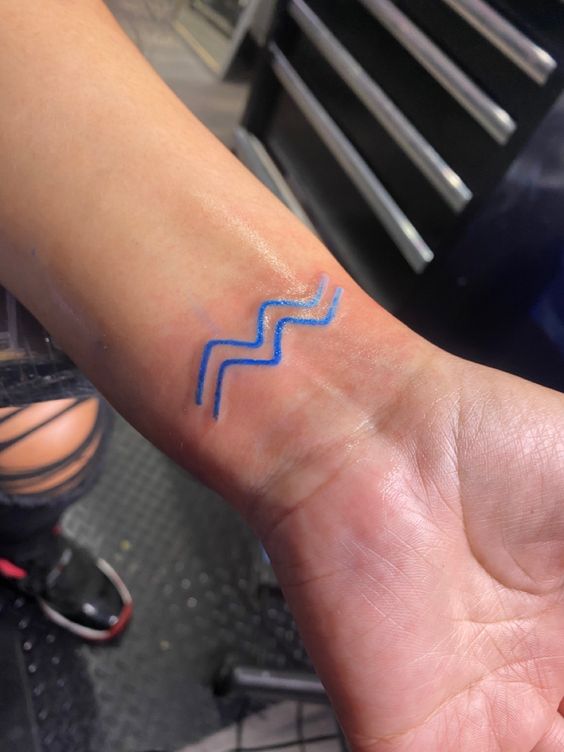 Tatouage Signe Verseau à L'encre Bleue Sur Le Poignet