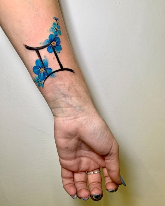 Tatouage Signe Gémeaux Avec Fleurs Bleues Sur L'avant Bras
