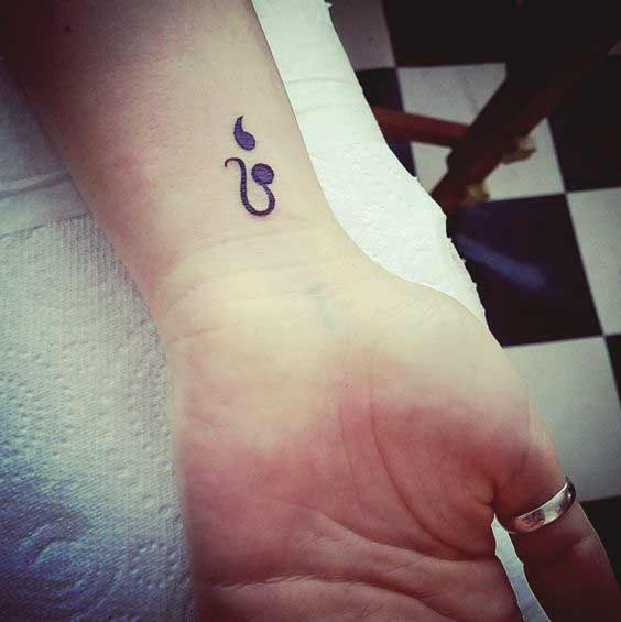 Tatouage Signe Lion Et Virgule Sur Le Poignet