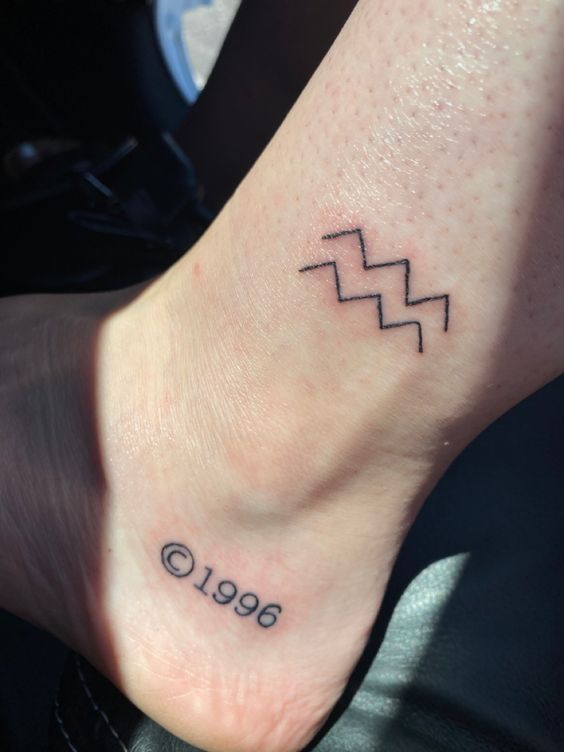 Tatouage Signe Verseau Et Année Sur La Cheville