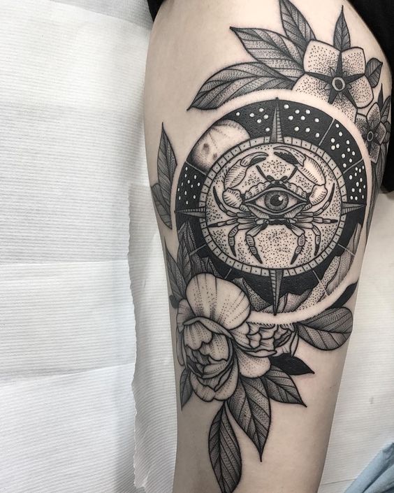 Tatouage Crabe Avec Oeil Et Fleurs En Noir Et Gris Sur La Cuisse