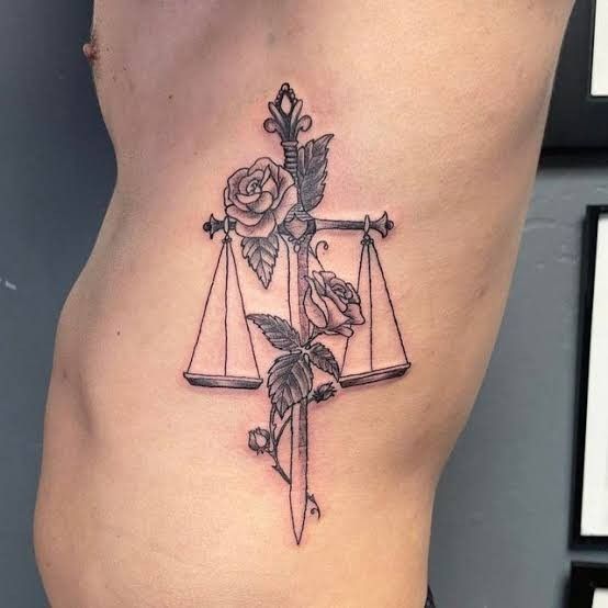 Tatouage Balance Avec épée Et Roses En Noir Et Gris Sur Les Côtes