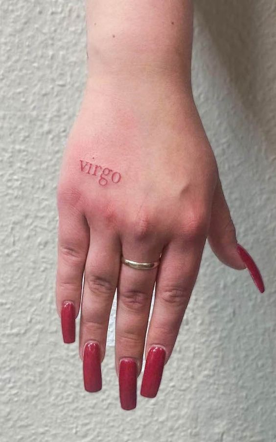 Tatouage Mot Virgo à L'encre Rouge Sur La Main
