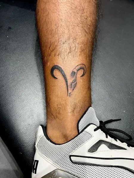 Tatouage Tête Et Signe Bélier Sur La Jambe