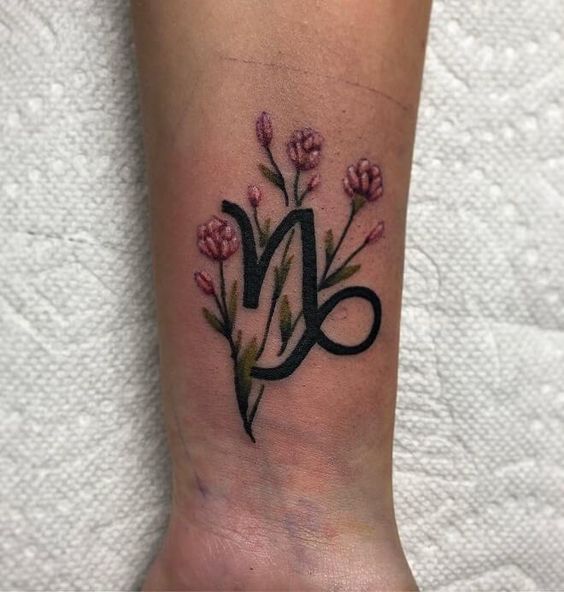 Tatouage Signe Capricorne Et Fleurs Rouges Sur Le Poignet