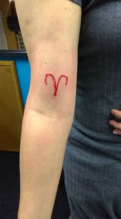 Tatouage Signe Bélier à L'encre Rouge Sur Le Bras