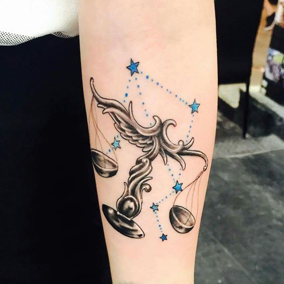 Tatouage Balance En Noir Et Gris Avec Constellation Bleue Sur L'avant Bras