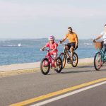 Mère, père et enfant à vélo près de la mer