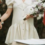 A Woman In A White Dress Holding A Bouqu